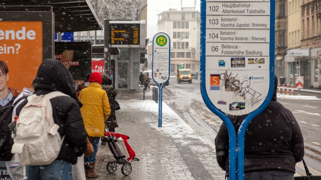 Wartende an verschneiter Bushaltestelle