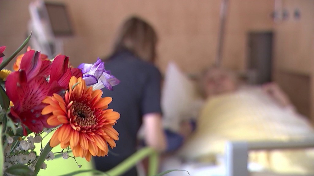 Foto: Eine ältere Frau liegt in einem Bett in einer Pflegeeinrichtung