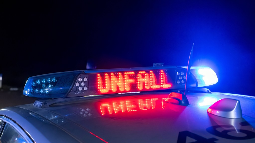 Schild auf einem Polizeiwagen warnt vor einem Unfall