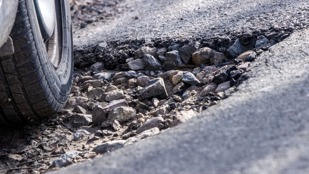 Ein Auto fährt durch ein Schlagloch.