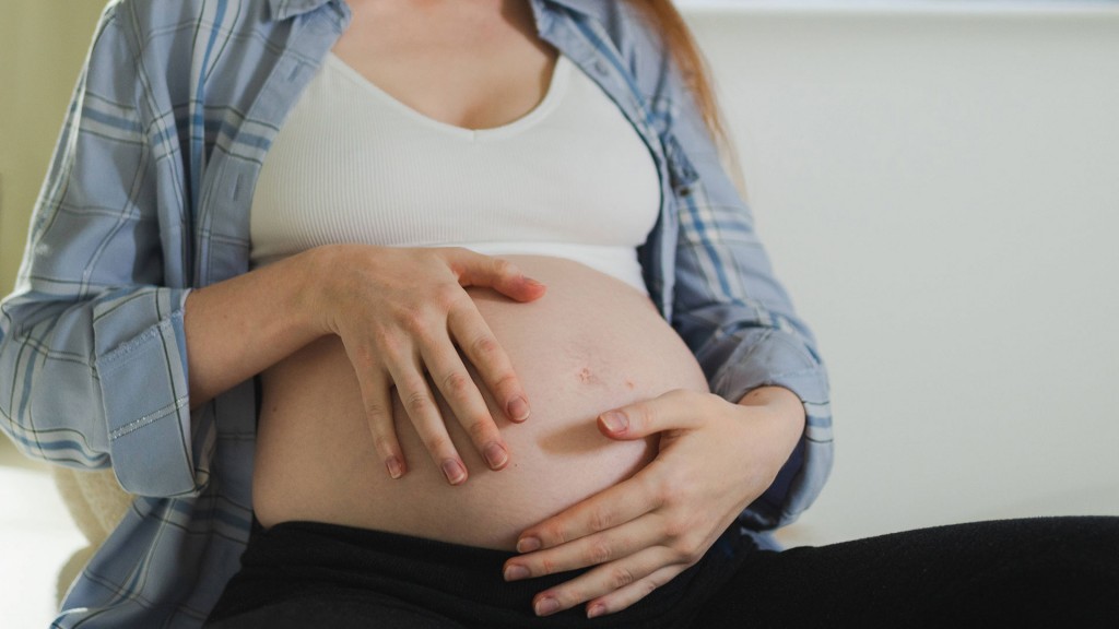 Eine Schwangere Frau umarmt ihren Bauch