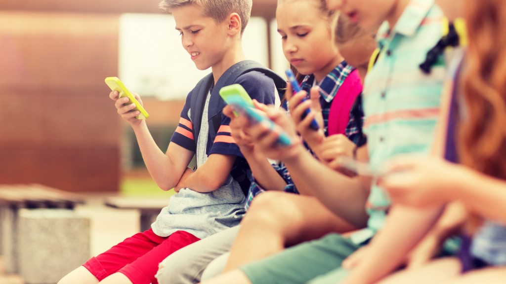 Schüler sitzen in der Pause zusammen und schauen auf ihre Smartphones