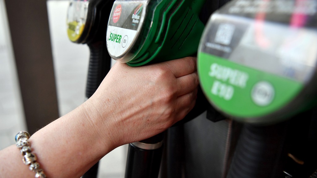 Eine Hand greift nach einer Zapfpistole an der Tankstelle