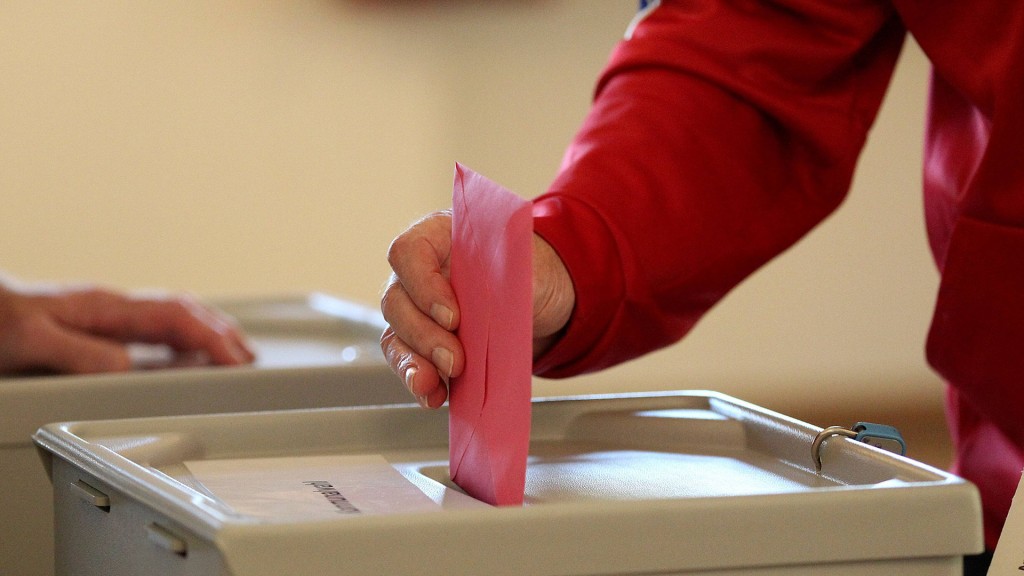 Eine Person wirft Stimmzettel in die Wahlurne