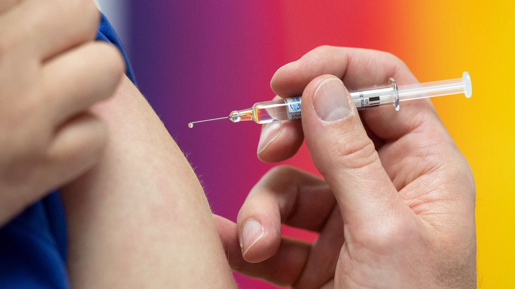 Eine Spritze mit Schutzimpfung vor einem Kinder-Arm