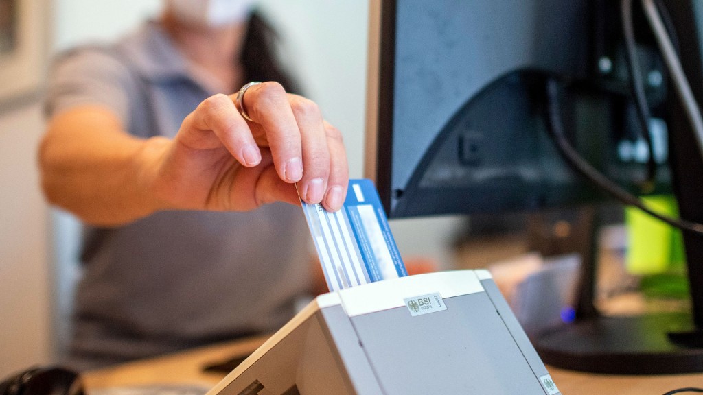 Eine Medizinische Fachangestellte schiebt in einer Hausarztpraxis die Versichertenkarte der Krankenkasse eines Patienten in das Lesegerät