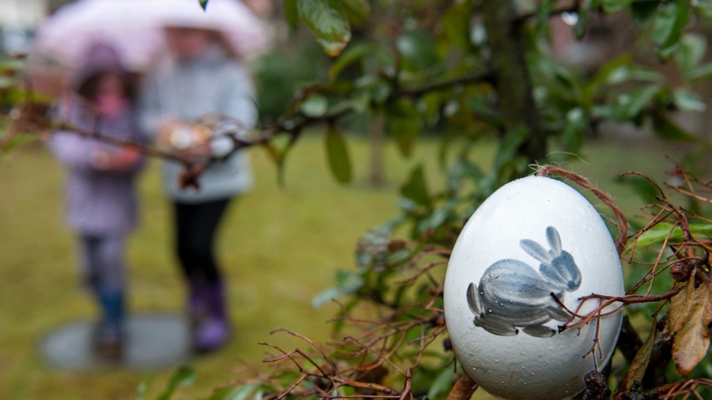 Bei Regen suchen Kinder Ostereier. Im Vordergrund ein bemaltes Ei.