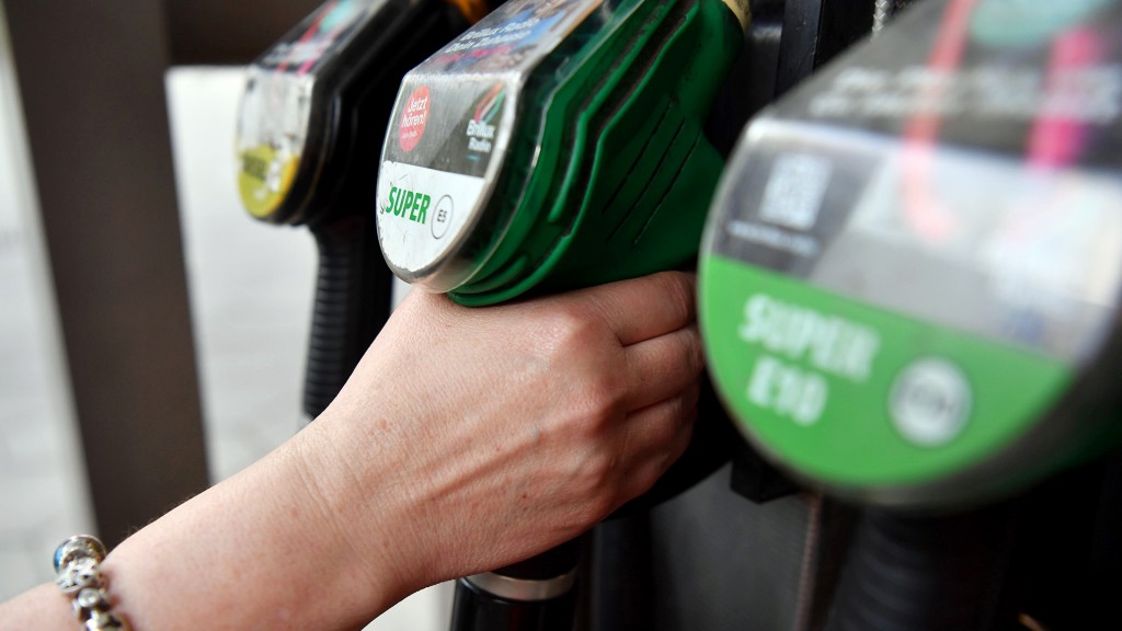 Foto: Eine Hand greift nach einer Zapfpistole an der Tankstelle