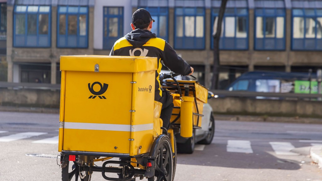 Ein Briefträger der Deutsche Post unterwegs mit seinem Fahrrad.