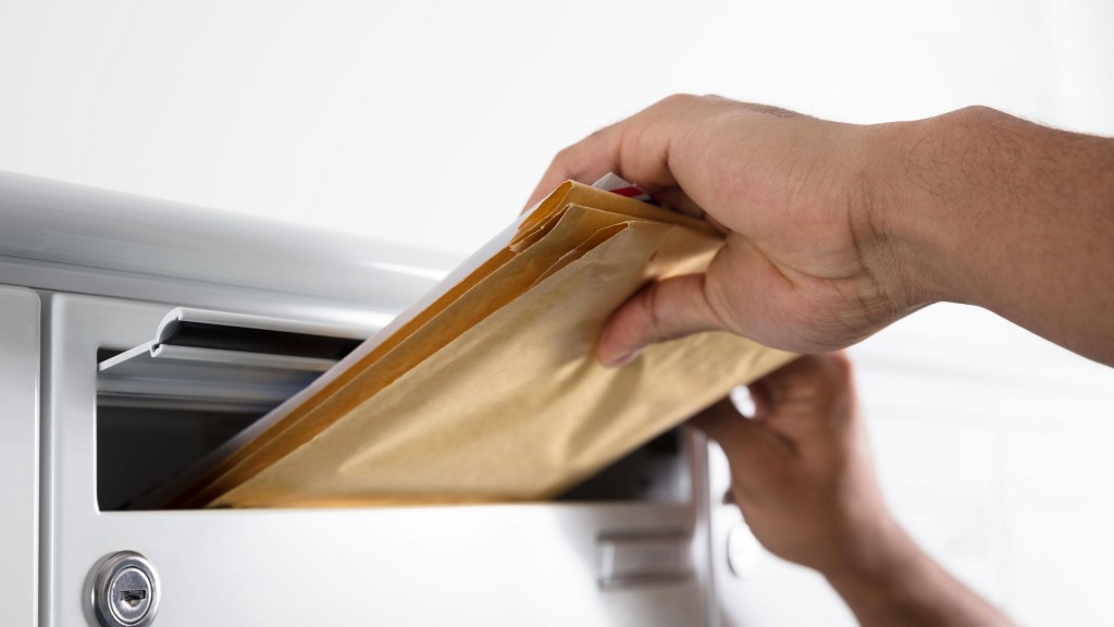 Ein Postbote steckt Briefe in einen Briefkasten.