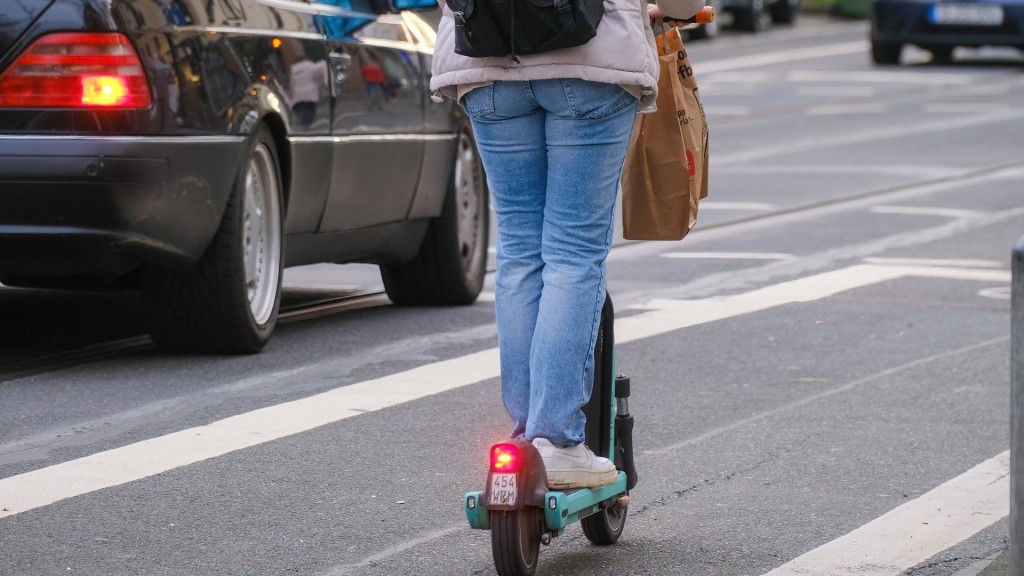 Eine Frau unterwegs auf einem E-Scooter auf der Straße.