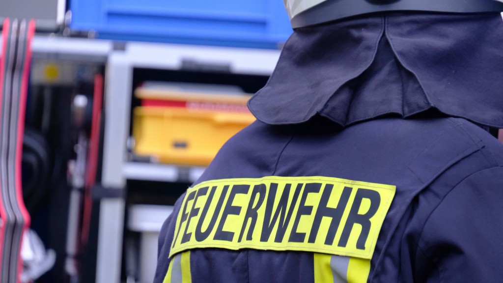 Foto: Symbolbild Feuerwehr. Ein Feuerwehrmann steht vor dem Einsatzwagen.