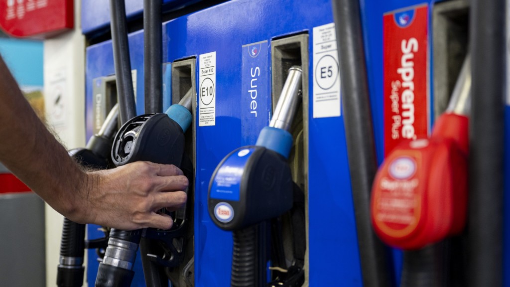 Foto: Ein Autofahrer hängt an einer Tankstelle eine Zapfpistole in die Zapfsäule. 