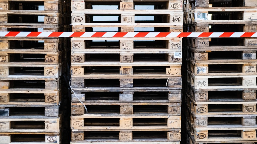 Symbolbild. Zurückgehende Aufträge. Mehrere Stapel Euro-Paletten stehen ungenutzt in einem Lager.