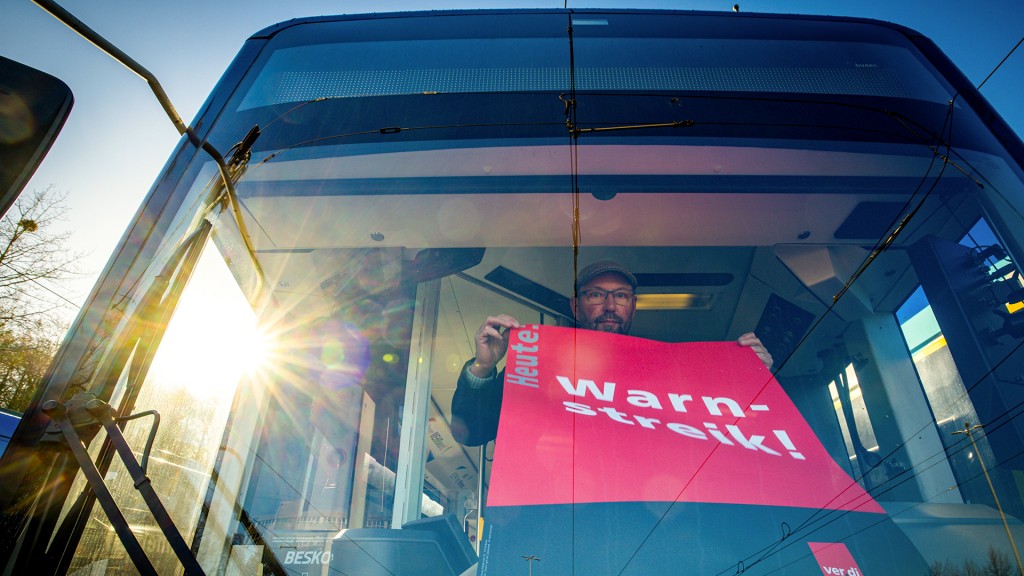 Foto: Ein Streik-Plakat der Gewerkschaft Verdi wird in die Frontscheibe eines Linienbusses gehängt
