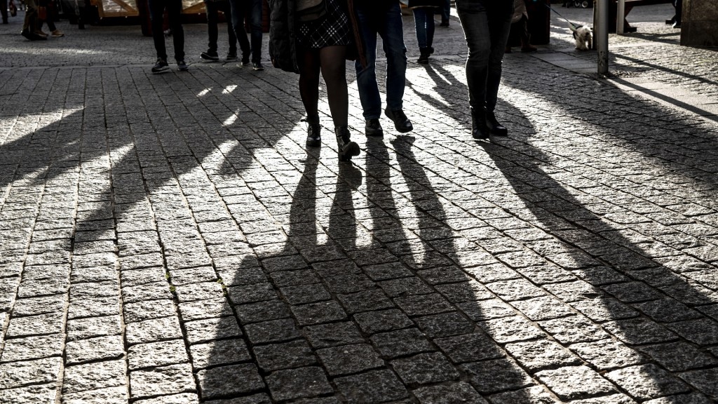Fußgänger werfen lange Schatten auf das Pflaster