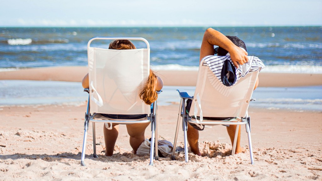 Zwei Urlauber sitzen am Strand in der Sonne