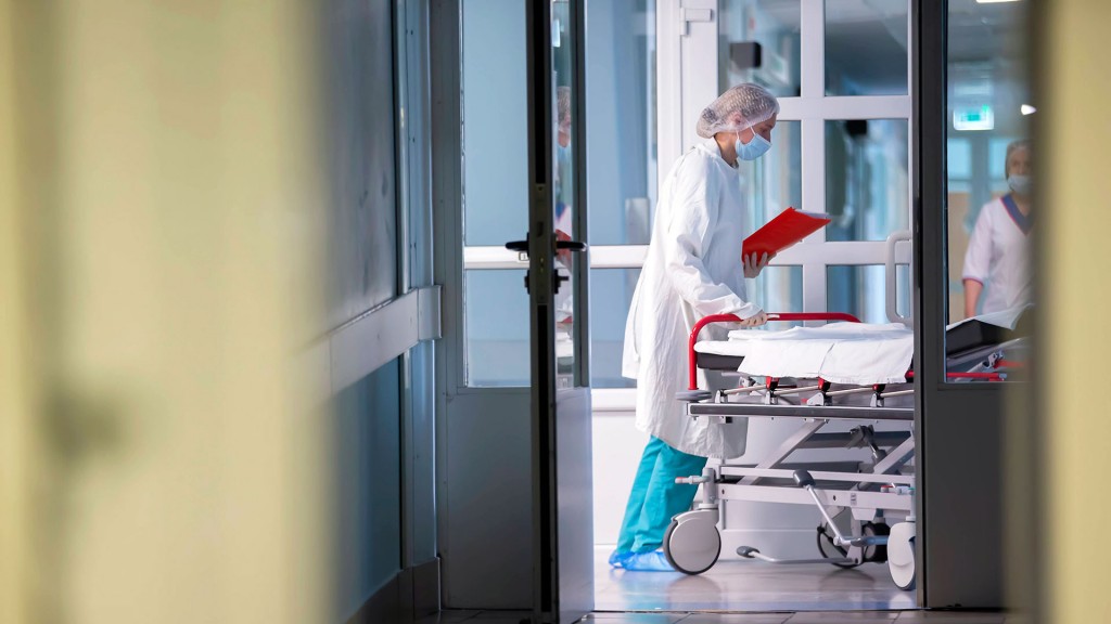 Foto: Krankenhauspersonal schiebt ein leeres Patientenbett über den Flur