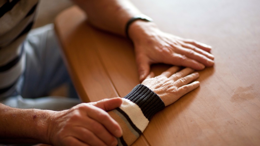Foto: Ein Mann hält die Hand seiner Ehefrau, die an Alzheimer erkrankt ist