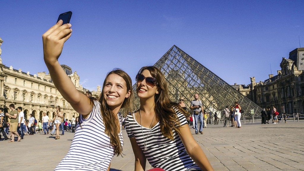 Foto: Zwei junge Frauen fotografieren sich vor dem Louvre in Paris