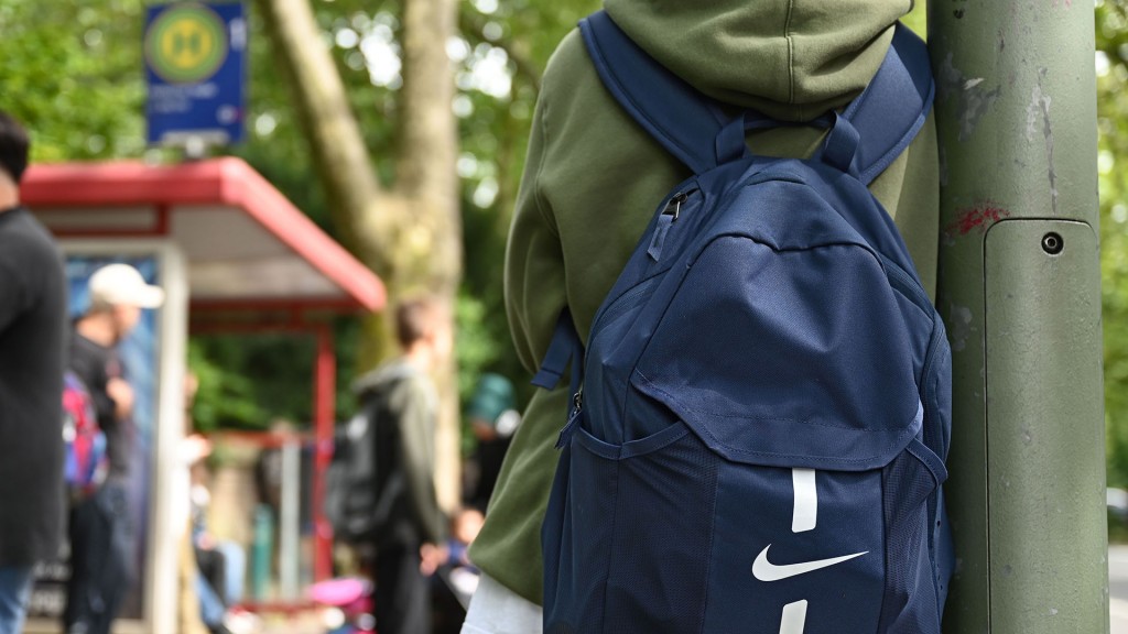 Foto: Ein Schüler mit Rucksack wartet an einer Haltestelle auf den Bus