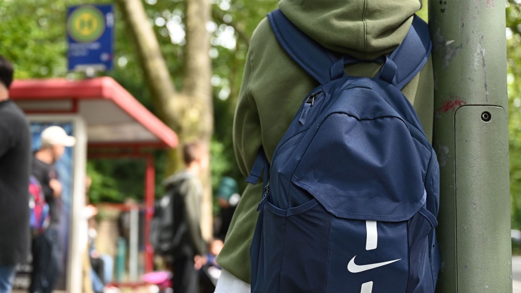 Ein Schüler mit Rucksack wartet an einer Haltestelle auf den Bus