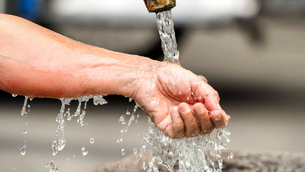 Foto: Frau lässt kaltes Wasser über ihr Handgelenk laufen