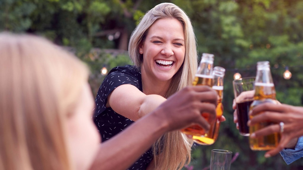 Frau prostet mit einer Bierflasche