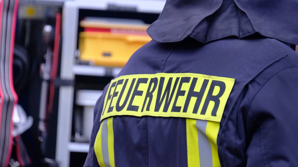 Symbolbild Feuerwehr. Ein Feuerwehrmann steht vor dem Einsatzwagen.