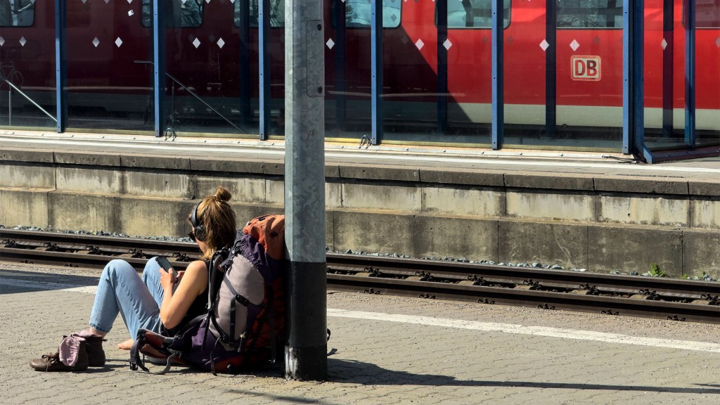 Eine Rucksacktouristin sitzt auf dem Boden und wartet auf den Zug.
