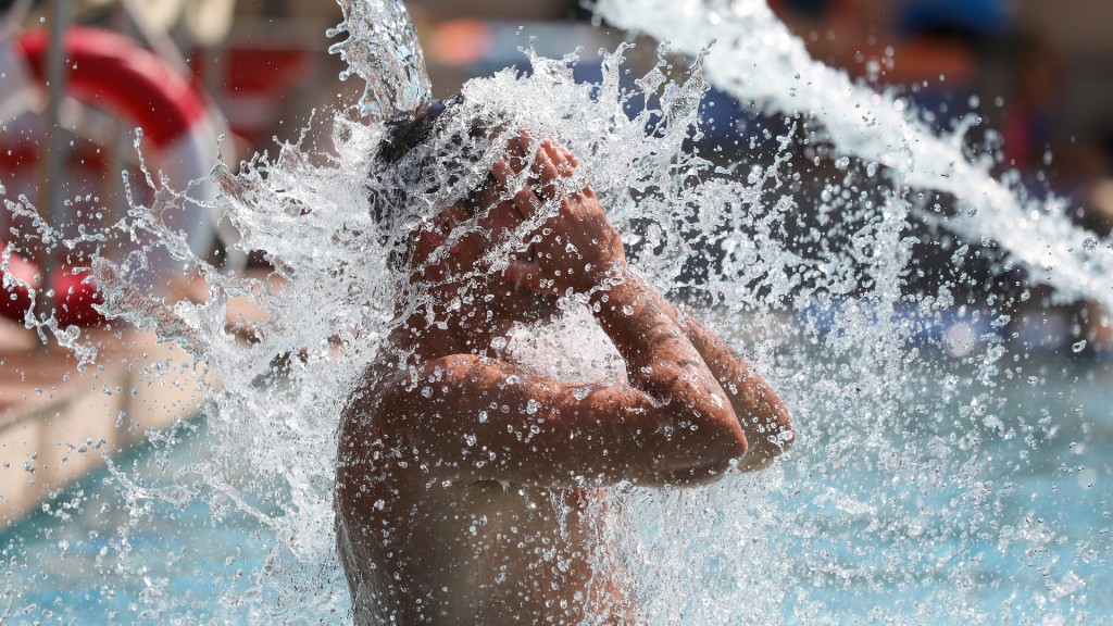 Ein Mann kühlt sich im Freibad ab.