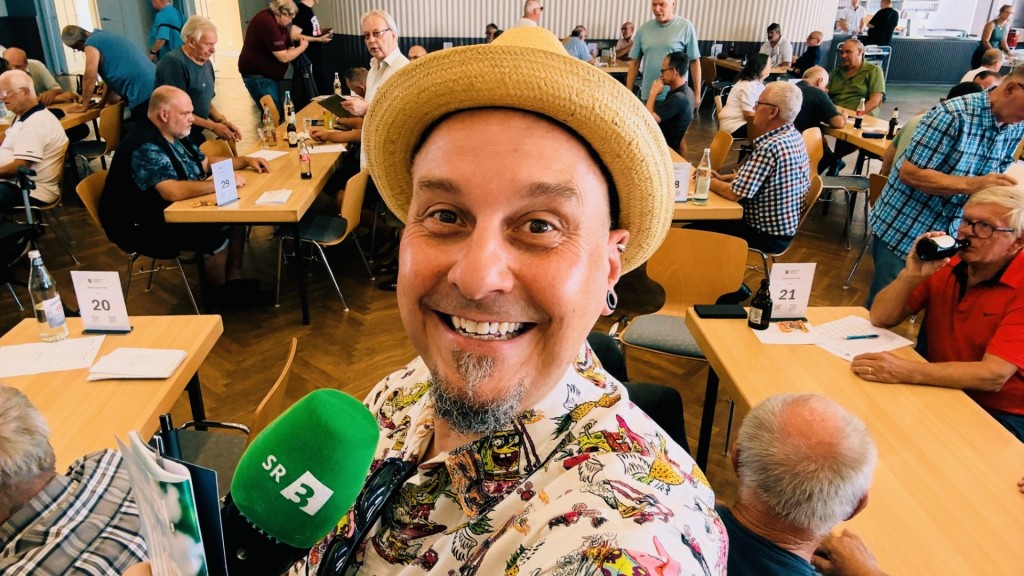 Freaky Jörn in einem Raum wo viele Menschen Skat spielen.