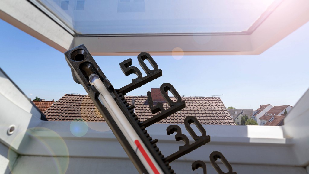 Ein Thermometer vor einem Dachfenster zeigt heiße Raumtemperatur an