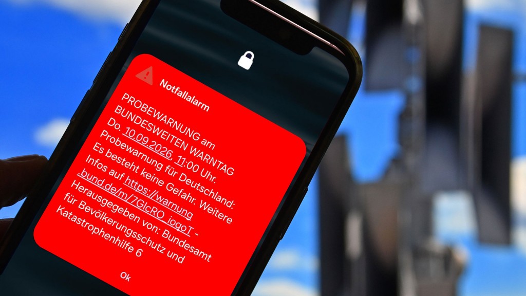 Bildmontage: Cell Broadcast Notfallwarnung auf dem Sperrbildschirm eines Smartphones vor Sirenen im Hintergrund