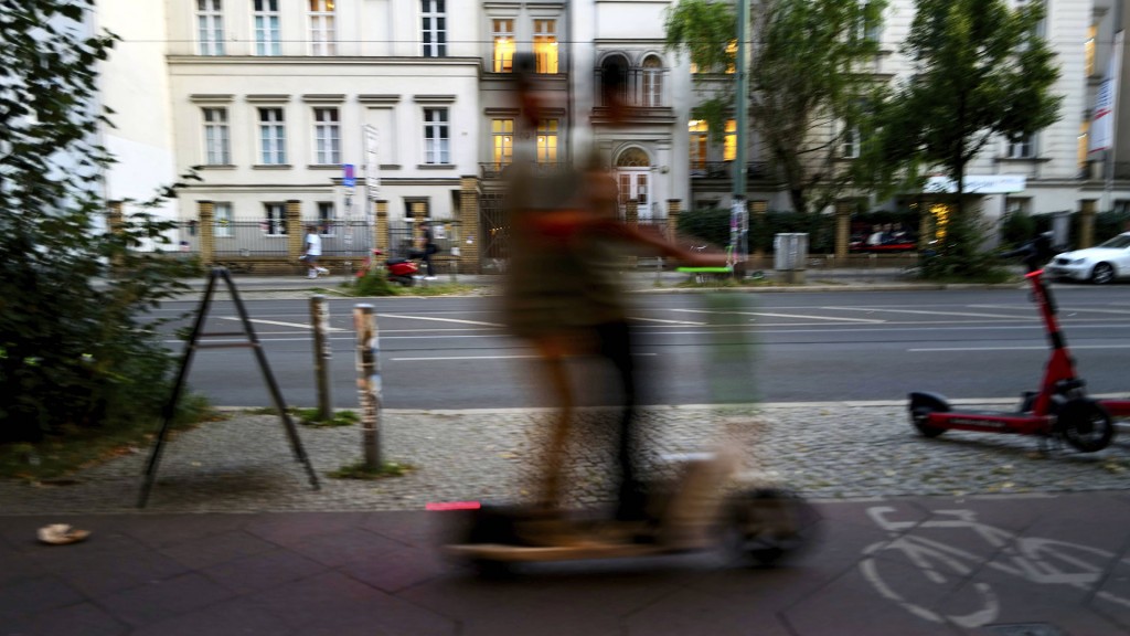 Zwei Personen fahren verwischt auf einem E-Roller vorbei