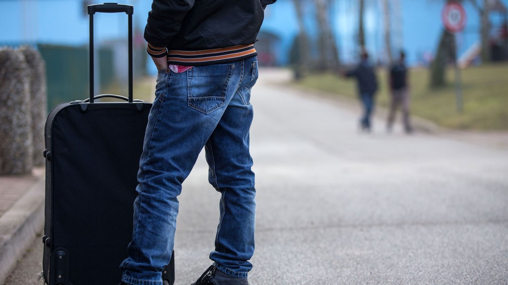 Foto: Eine Person steht neber einem Koffer